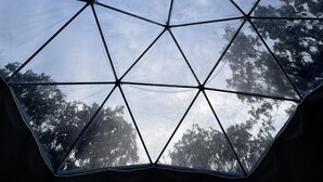 A geodesic dome structure with a clear sky view through its triangular sections. - The Starman Dome (Saint Jo)
