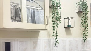 Casa de banho com lavatório, sanita e janela acima do espelho.