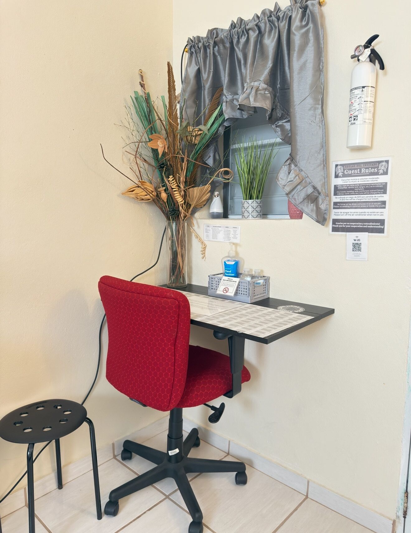 A small office space with a desk, chair, and a window with curtains.