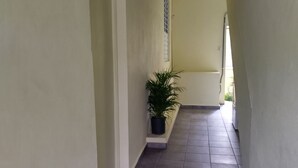 Corredor estreito com chão de azulejos e paredes claras.