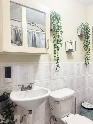 A bathroom with a sink, toilet, and a window above the mirror.