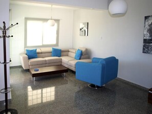 A modern living room with a beige sectional sofa, a blue armchair, and a coffee table.