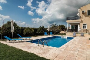 A rectangular swimming pool with a tiled deck, surrounded by lounge chairs and umbrellas. - Luxury, Modern Villas with private pool & garden in Coral Bay area (Πέγεια, Πάφος)