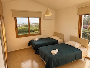 A hotel room with two beds, a large window with a view, and a ceiling light. - Luxury, Modern Villa with private pool & garden in Coral Bay area (Πέγεια, Πάφος)