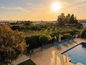 A pool area with lounge chairs and a bench, surrounded by greenery and buildings. - Luxury, Modern Villa with private pool & garden in Coral Bay area (Πέγεια, Πάφος)