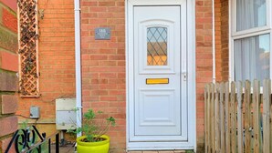 A white door with a small window, a yellow mailbox, and a wooden fence. - Bedford Road Garden Apartment (Bedford)