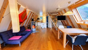 Acogedor dormitorio en el ático con sofá, mesa de comedor y televisor.