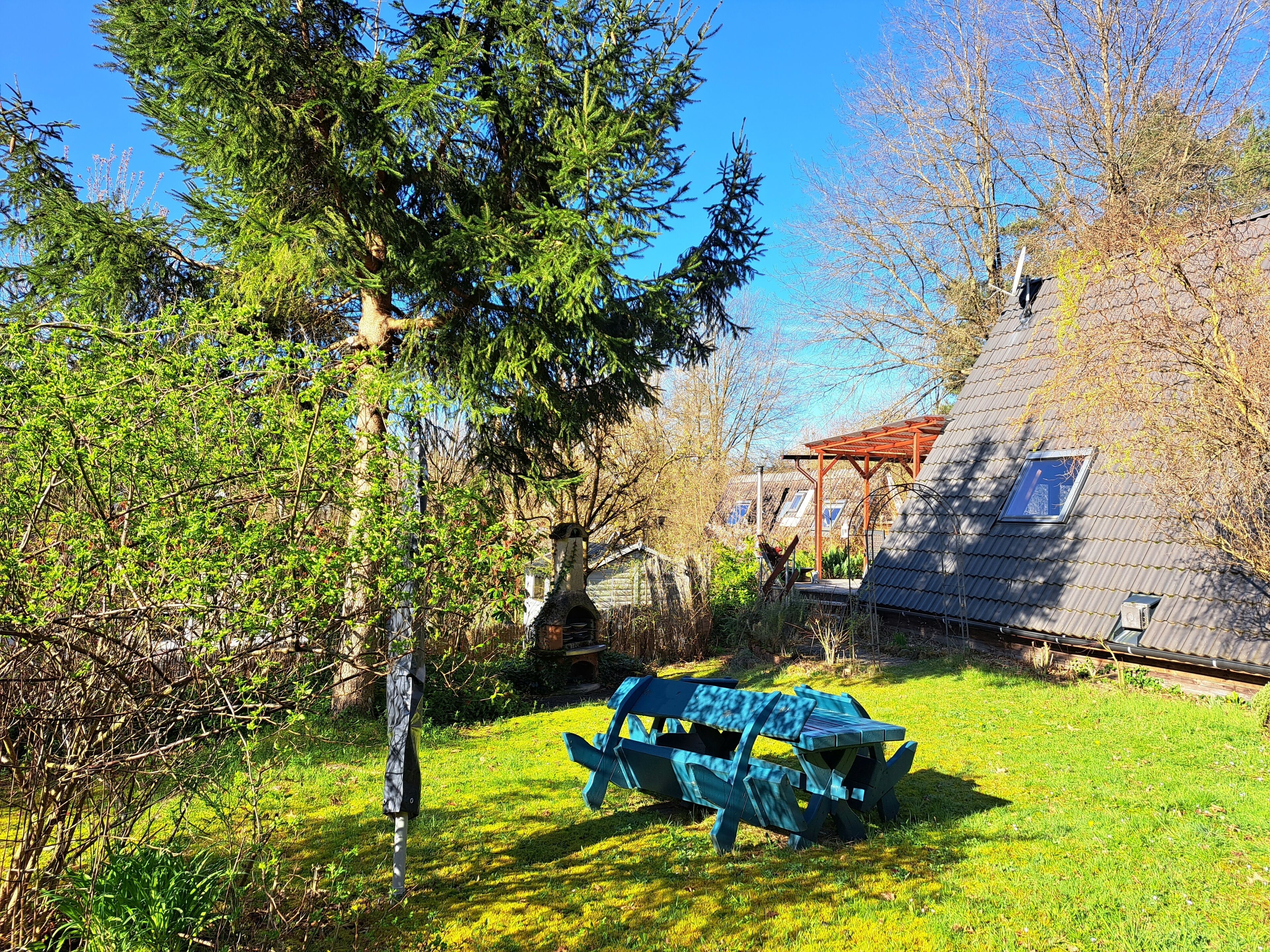 Un jardin avec une table de pique-nique, un nichoir et une maison avec un toit en pente.