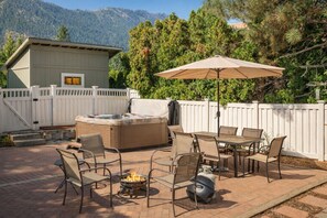 Un patio al aire libre con un jacuzzi, asientos y una chimenea.