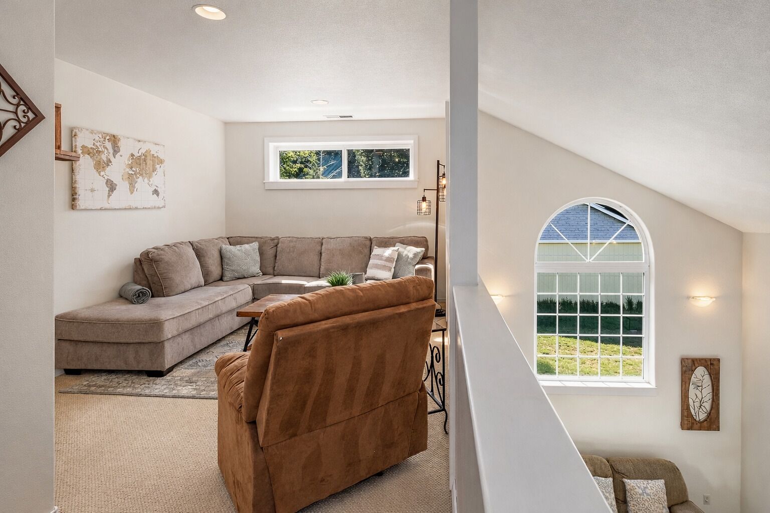 A spacious loft bedroom with a large window, a curved ceiling, and a cozy seating area.