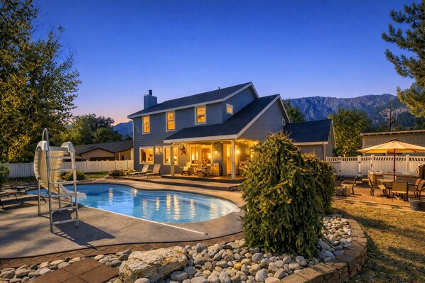 Une maison à deux étages avec une piscine, un espace salon extérieur et une vue sur les montagnes.