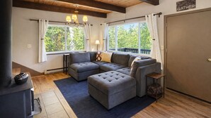 A cozy living room with a sectional sofa, a fireplace, and a 'GATHER' sign on the wall.