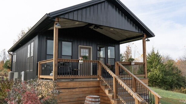 A modern house with a wooden deck, a staircase, and a covered porch.