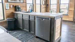A compact kitchen with a sink, dishwasher, and a small trash bin.