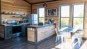 A modern kitchen with wooden walls, stainless steel appliances, and a central island.