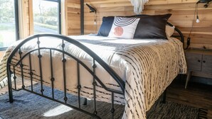 A bed with a metal frame, a patterned bedspread, and a pillow with a circular design.