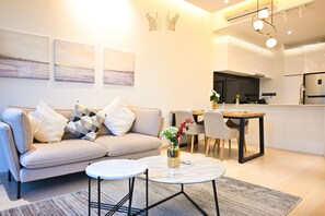 Un salon moderne avec un canapé, deux tables rondes et un coin repas avec des chaises.