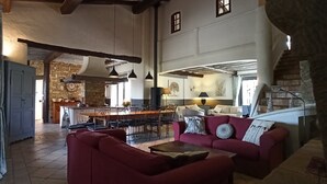 A spacious living area with a red sofa, a dining table, and a kitchen in the background. - Le Mas du Colombier - Les Vans - Ardèche Méridionale (Les Vans)