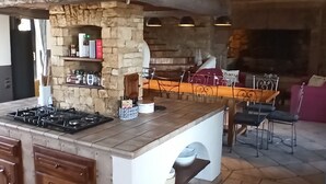 A kitchen with a stone island, wooden cabinets, and a stone fireplace. - Le Mas du Colombier - Les Vans - Ardèche Méridionale (Les Vans)