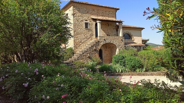 An old stone building with a tiled roof, surrounded by lush greenery and flowering plants. - Le Mas du Colombier - Les Vans - Ardèche Méridionale (Les Vans)