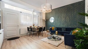 Una sala de estar moderna con un sofá azul, una mesa redonda y un comedor con mesa y sillas.