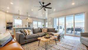 A modern living room with a grey sectional sofa, a wooden coffee table, and a ceiling fan. - Private Pool & Hot Tub • Rooftop Fire Pit • Sleeps 20 • Near Zion (Washington)