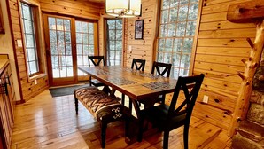 A wooden interior with a large dining table, chairs, and a bench. There are large windows and a fireplace. - Secluded Tustin Cabin with Fire Pit and Hiking Trails (Tustin)