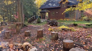 A rustic cabin surrounded by a forest with a fire pit and wooden stumps. - Secluded Tustin Cabin with Fire Pit and Hiking Trails (Tustin)