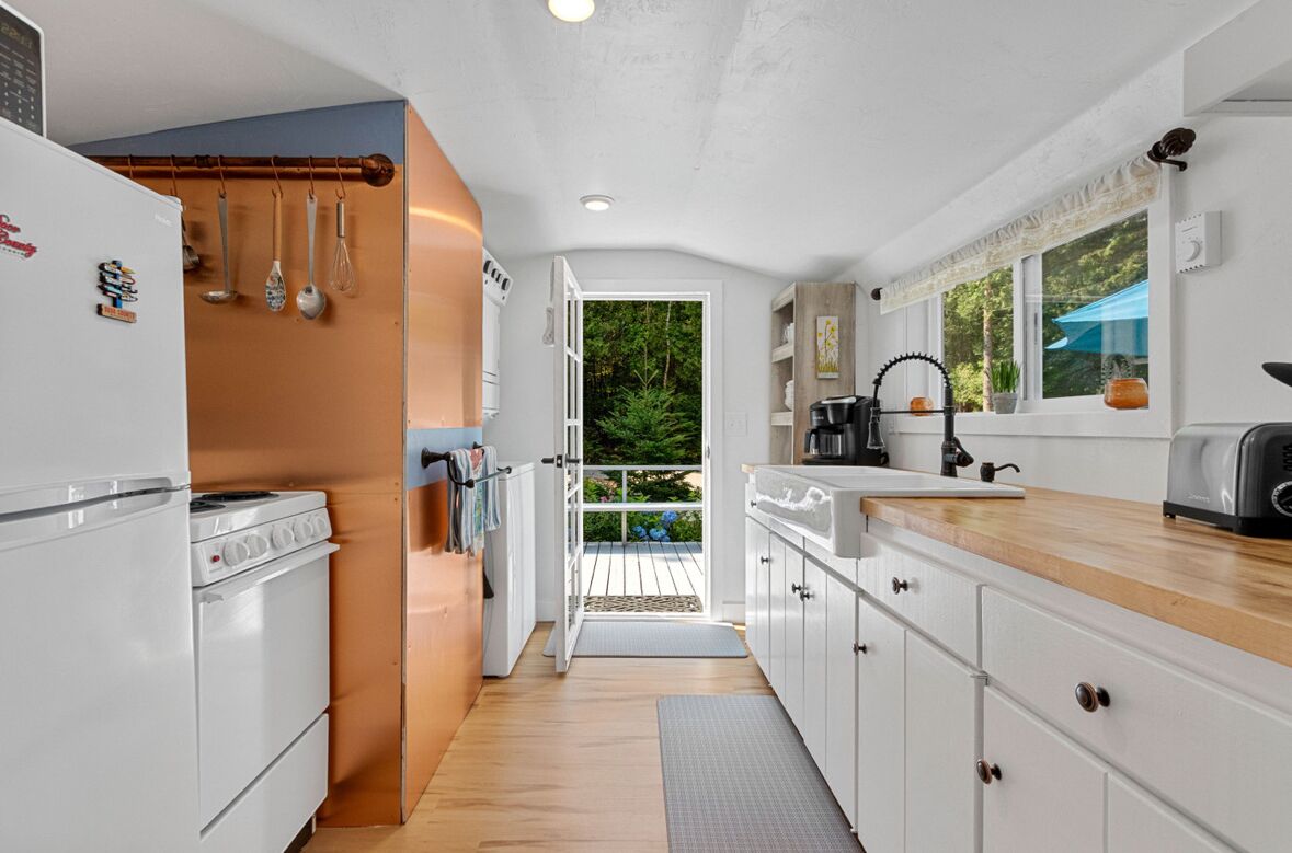 A modern kitchen with white cabinets, a wooden countertop, and a view of the outdoors.