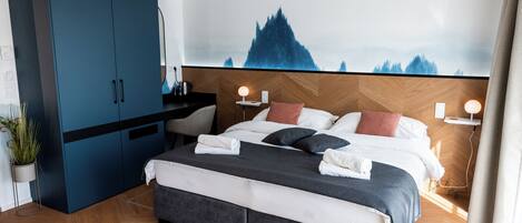 Et moderne hotelværelse med en stor seng, et klædeskab, et skrivebord og en lampe på væggen.