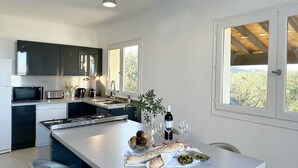 Een moderne keuken met donkere kastjes, een groot eiland en uitzicht op de omgeving.
