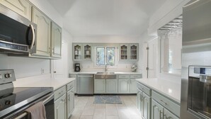 Een moderne keuken met roestvrijstalen apparatuur, lichtgroene kastjes en een centraal kookeiland.