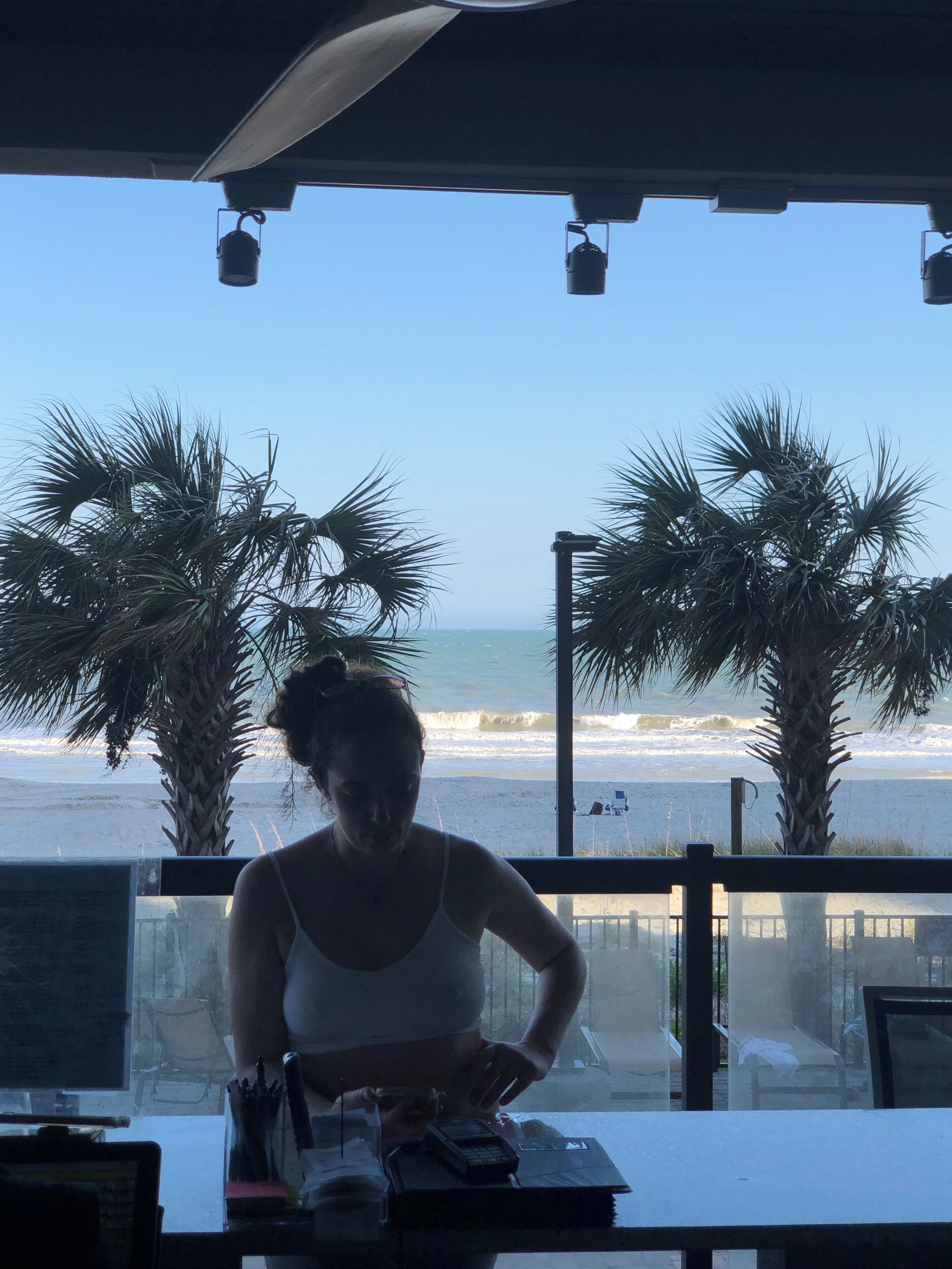 Una donna al lavoro a un tavolo con vista sulla spiaggia e sull'oceano.