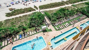 Ein Resort mit mehreren Schwimmbecken, Liegestühlen und einem Strandbereich mit Sonnenschirmen.