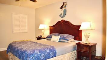 A neatly made bed with a blue and white patterned bedspread, two bedside lamps, a wooden nightstand, and a wall-mounted decorative piece.