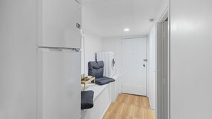 A narrow hallway with a built-in bench, a washing machine, and a door leading to another room. - The Nifty Nook Studio with Parking and Wi-fi (Auckland West)