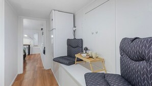 A compact living space with a kitchenette, a sofa, and a small table with a tray. - The Nifty Nook Studio with Parking and Wi-fi (Auckland West)