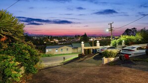 A parking area with cars, a building with a green roof, and a sunset sky. - The Nifty Nook Studio with Parking and Wi-fi (Auckland West)