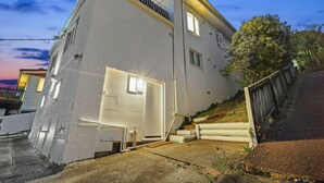 A two-story building with a white exterior, a visible door, and a small window. - The Nifty Nook Studio with Parking and Wi-fi (Auckland West)