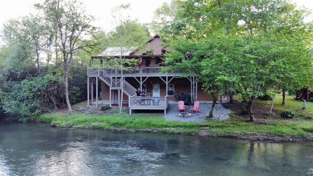 A cabin with a deck and a covered porch, situated by a river. - Riverfront Cabin w/ Porch & Firepit - Peaceful Retreat Near Murphy, NC. (Murphy)