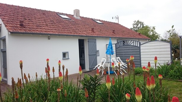 A white house with a red-tiled roof, a grey door, and a small window.
