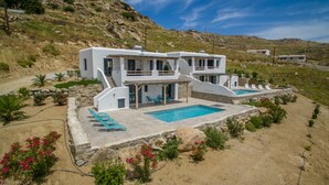 Ein modernes, zweistöckiges Haus mit Pool, umgeben von einem angelegten Garten und einer felsigen Hangkante.