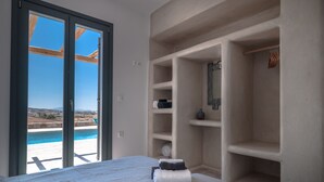 Ein Schlafzimmer mit großem Fenster, einem Bett und eingebauten Regalen.