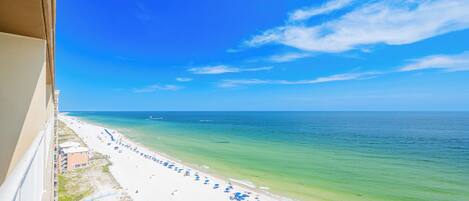A beach with white sand, clear turquoise water, and a clear blue sky.