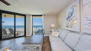 Una habitación con balcón, un sofá, una mesa y un cuadro.