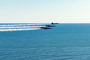 A group of aircraft flying over a body of water.