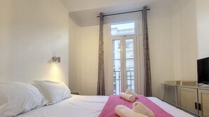 Ein Hotelzimmer mit Bett, Fernseher und einem Fenster mit Vorhängen.