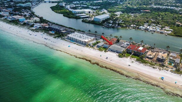 Oversigtsbillede af et kystområde med strand, lystbådehavn og bygninger ud til vandet.