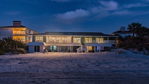 En ejendom ved stranden med en stor, flereetagers bygning, der har både altaner og store vinduer.
