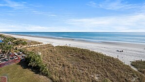 A beach with a wooden walkway and a grassy area.